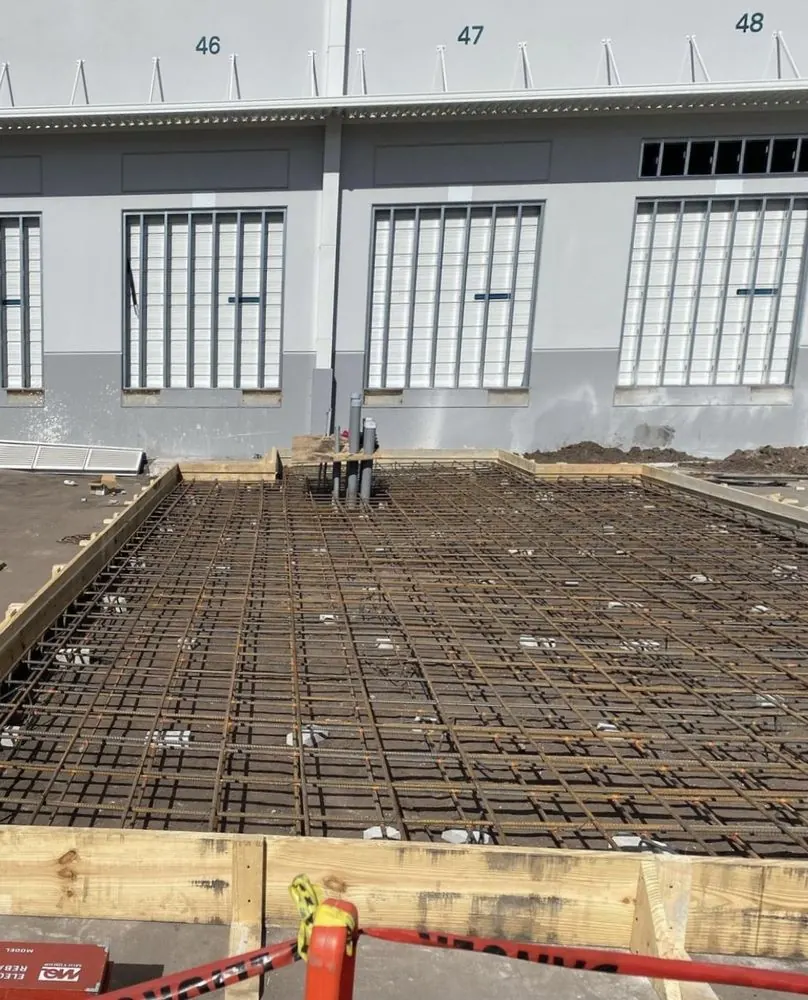 Loading dock slab preparation with rebar grid and formwork at warehouse bays